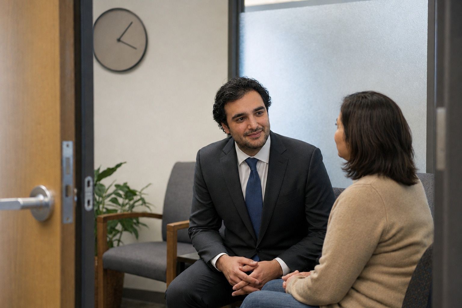 Alexander Susi in a waiting room, a clock on the wall behind him